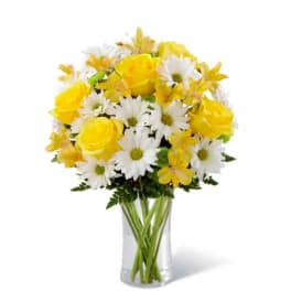 Yellow roses and white daisies in a clear glass vase
