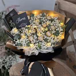 Bouquet of white baby's breath with small gold-wrapped chocolates and warm lights