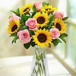 Bouquet of pink roses and yellow sunflowers in a clear glass vase