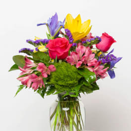 Colorful bouquet of roses, lilies, and alstroemeria in a clear glass vase