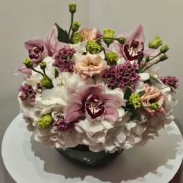 Pink orchids and white hydrangeas arranged in a dark vase