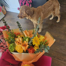 Orange and yellow mixed bouquet wrapped in orange paper with a ribbon