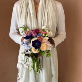 Person holding a colorful bridal bouquet with mixed flowers