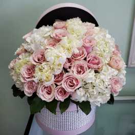 Pink roses and white hydrangeas in a round pink hatbox