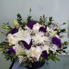 White lilies and roses with purple blooms in a black vase