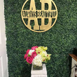 Pink roses and white flowers in a square glass vase on a pedestal