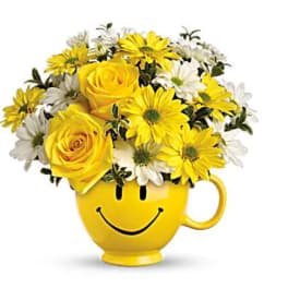 Yellow roses and white daisies in a smiley-face mug