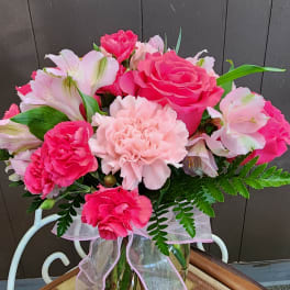 Pink and white flower bouquet in a glass vase with a ribbon
