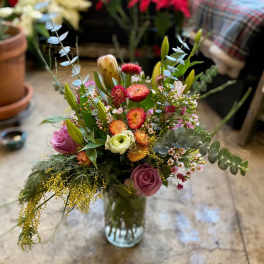 Mixed bouquet of pink, orange, and white flowers in a glass vase