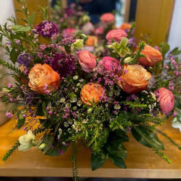 Mixed bouquet of orange and pink roses with purple filler flowers