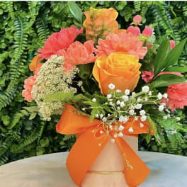 Bouquet of orange and pink flowers in a vase with an orange ribbon