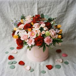 Mixed bouquet of roses, tulips, and daisies in a pink hat box