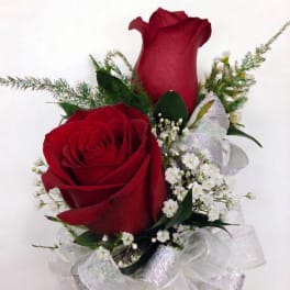Two red roses with white filler flowers and a sheer ribbon bow