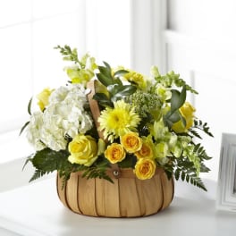 Yellow and white flower arrangement in a woven basket
