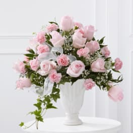 Pink roses and carnations arranged in a white vase