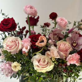 Mixed bouquet of roses and pink blooms in a green vase