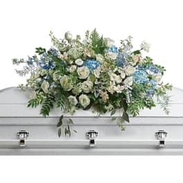 White and blue floral casket spray on a silver casket