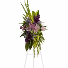 Tall purple and green floral arrangement on a clear stand