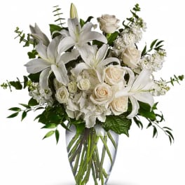 White lilies and roses arranged in a clear glass vase