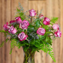 Pink roses arranged in a clear glass vase with fern foliage