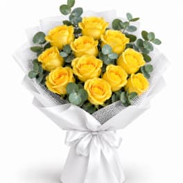 Bouquet of yellow roses wrapped in white paper with a satin bow