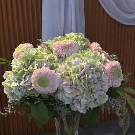 Pastel hydrangea and pink chrysanthemum arrangement in a clear glass vase