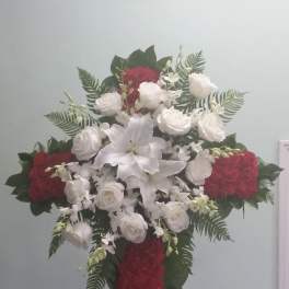 Cross-shaped floral spray with white lilies and roses and red flowers