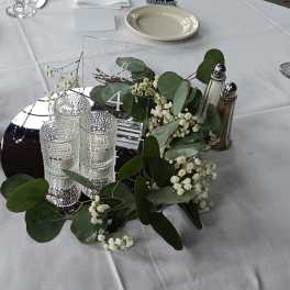 Round table centerpiece with greenery, baby's breath, and glass candle holders