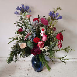 Mixed holiday bouquet in a blue glass vase with red, pink, and white flowers