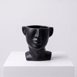 Black face-shaped vase on a white pedestal