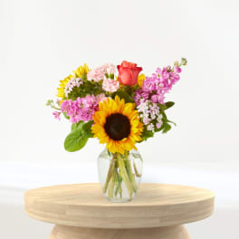 Mixed bouquet with a sunflower and rose in a clear glass vase