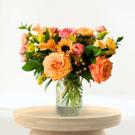 Mixed orange and pink flowers arranged in a clear glass vase