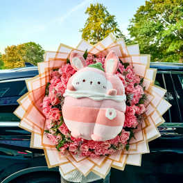 Pink flower bouquet with a plush bunny centerpiece