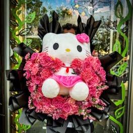 Hello Kitty plush surrounded by a pink flower arrangement