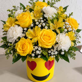 Yellow roses and white carnations in a smiley-face container