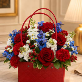Red roses, blue flowers, and white blooms arranged in a red basket