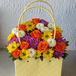 Basket arrangement of orange roses and colorful daisies