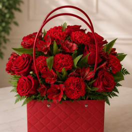 Red roses and carnations arranged in a red handled basket