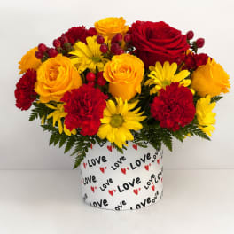 Red and yellow flowers arranged in a heart-themed box