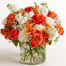 Orange and white flower bouquet in a clear glass vase