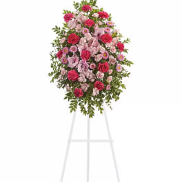 Standing floral spray with pink and red blooms on a white easel