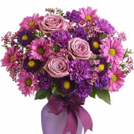 Pink and purple mixed bouquet with roses and daisies in a ribbon-tied vase