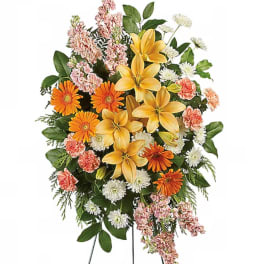 Standing floral spray with yellow lilies, orange daisies, and pink carnations