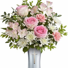 Pink roses and white flowers arranged in a vase with a cross emblem