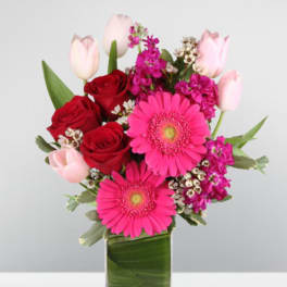 Pink and red mixed bouquet in a clear rectangular vase