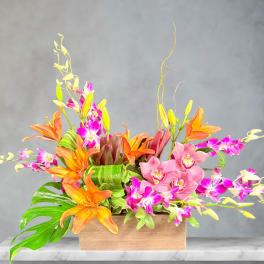 Orange lilies and pink orchids arranged in a wooden box