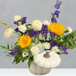 Floral arrangement in a white pumpkin-shaped vase with yellow and white blooms