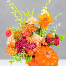 Orange pumpkin vase with mixed orange, pink, and purple flowers
