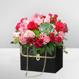 Pink and red rose bouquet in a black box with a gold chain handle