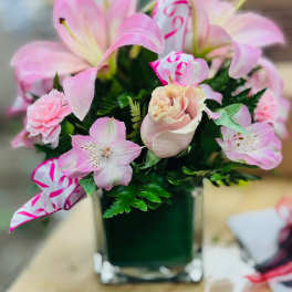 Pink lilies and roses arranged in a square glass vase